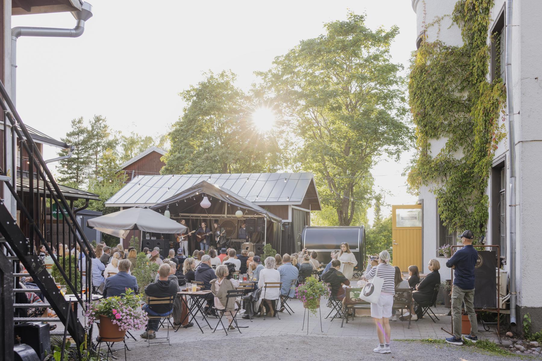 Ravintola terhon sisäpiha, ihmisiä terassilla musiikkilavan edessä