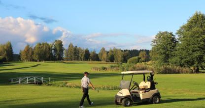 golf-kenttä ja golfin pelaaja golfauton kanssa