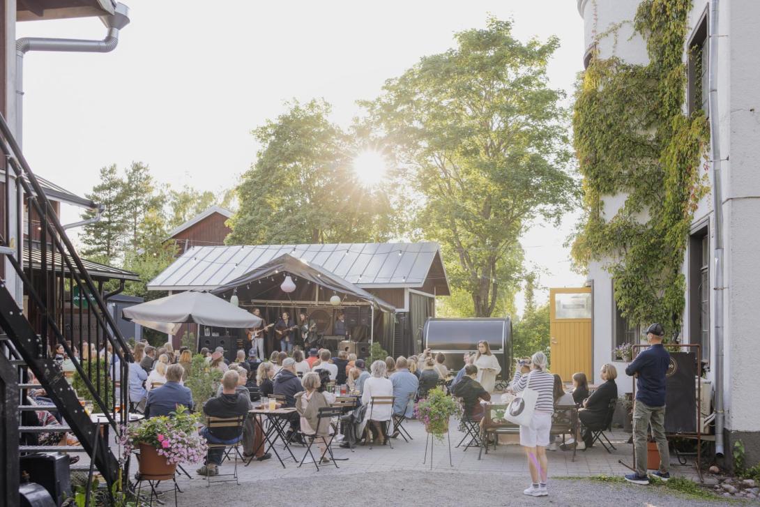 Ravintola terhon sisäpiha, ihmisiä terassilla musiikkilavan edessä
